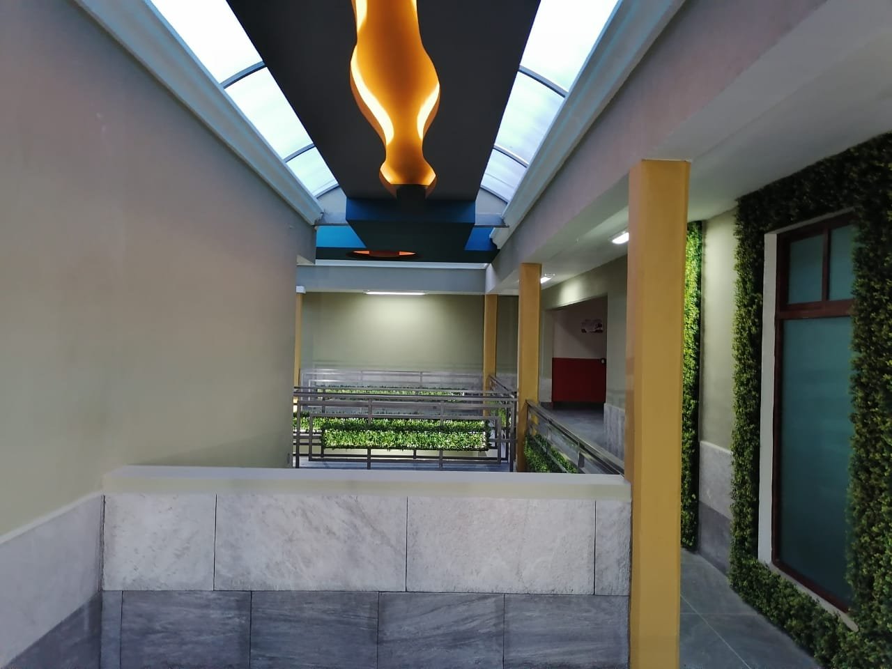Pasillo interior con tragaluz y jardineras integradas.