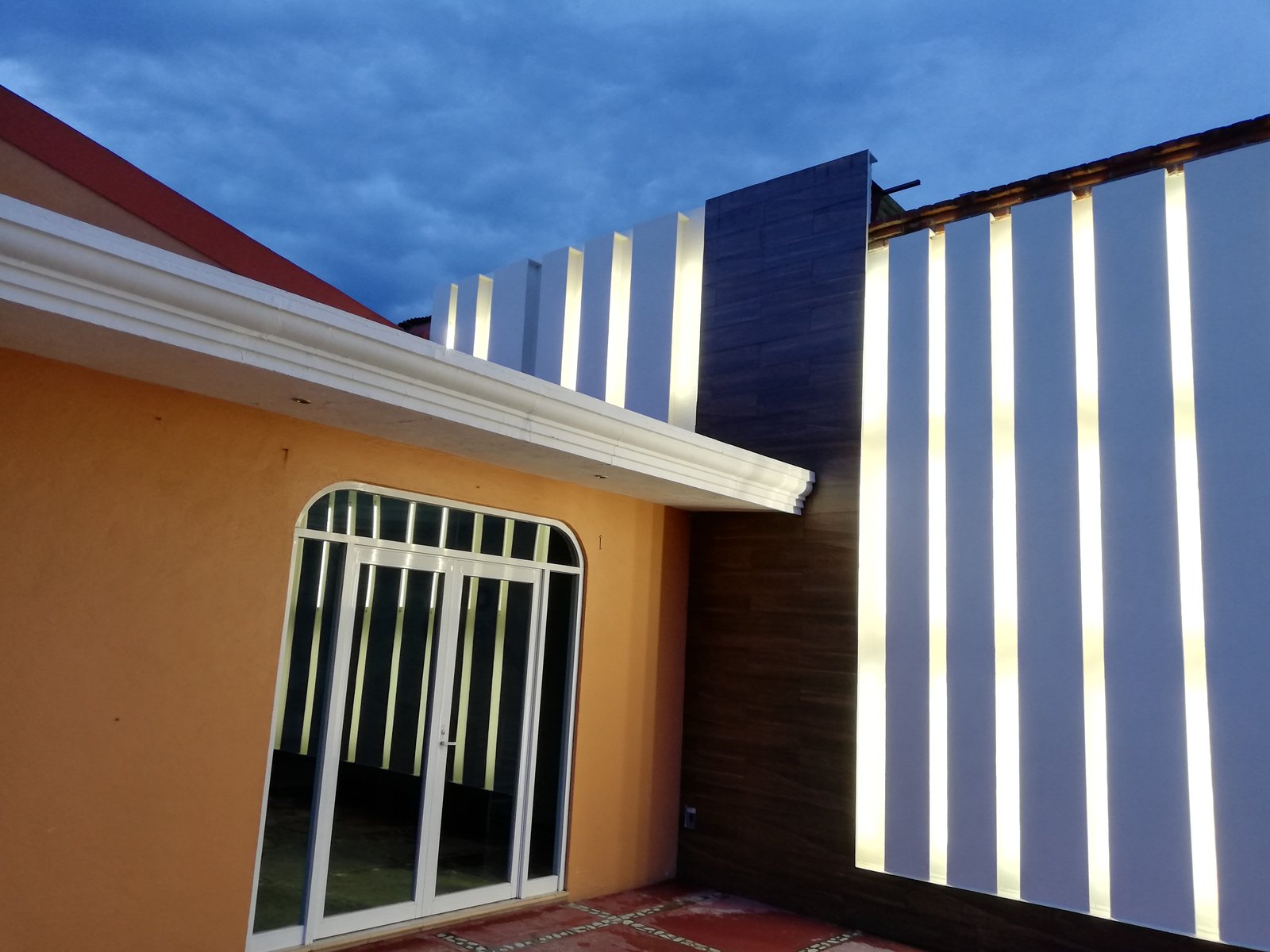 Acceso residencial con celosía vertical iluminada.