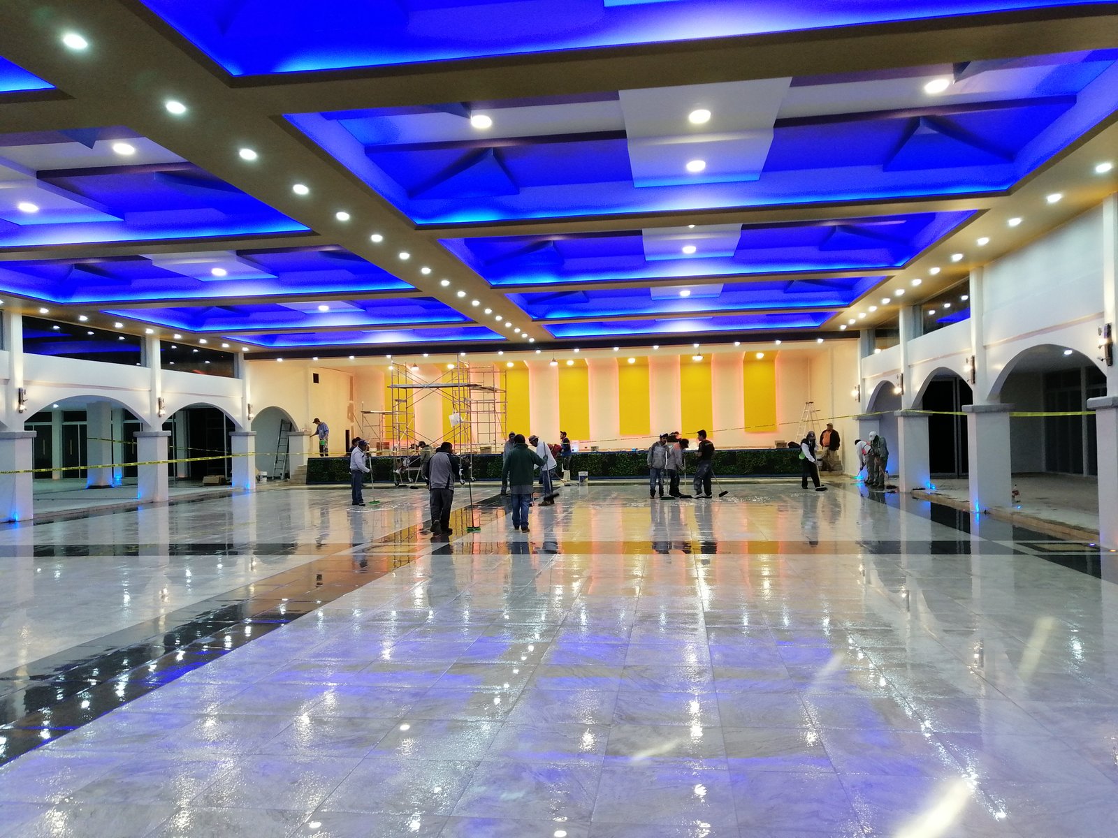 Salón amplio con plafón geométrico e iluminación azul.